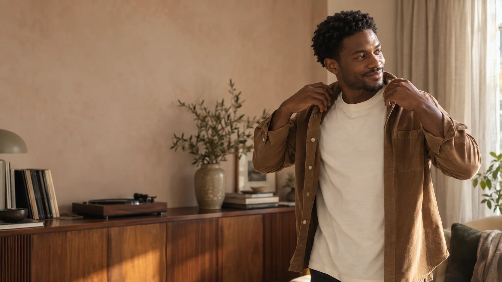 A man with natural curls getting ready in his sunlit apartment